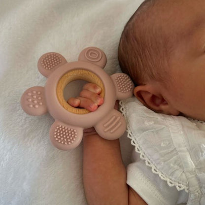 Bébé allongé tenant un anneau de dentition rose et beige en silicone