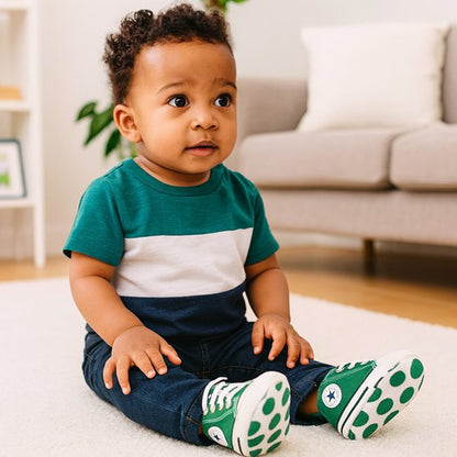 Bébé assis sur le sol portant des chaussure bébé souples ergonomiques adaptées aux premiers pas