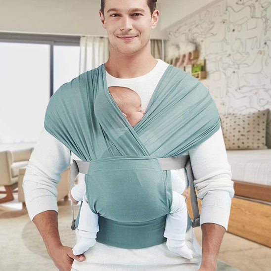 Bébé installé en position physiologique dans une écharpe de portage verte, soutien naturel de la colonne et des hanches.