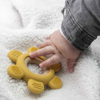 Bébé jouant avec un anneau de dentition jaune posé sur une couverture