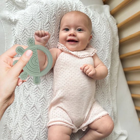Bébé jouant avec un anneau de dentition souple pour soulager ses gencives