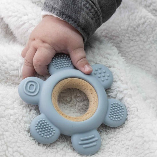 Bébé tenant un anneau de dentition en silicone bleu entre ses mains