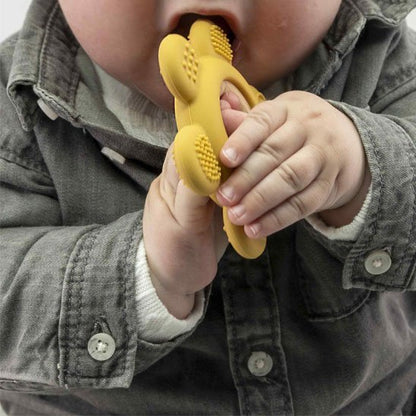Bébé tenant un anneau de dentition jaune en silicone avec reliefs