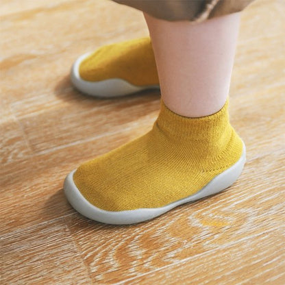 Chaussures bébé antidérapantes jaunes portées par un enfant debout