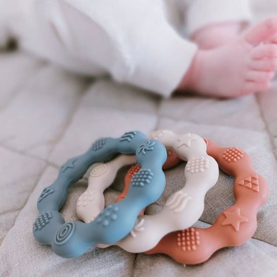 Main tenant un anneau de dentition en silicone pastel pour bébé