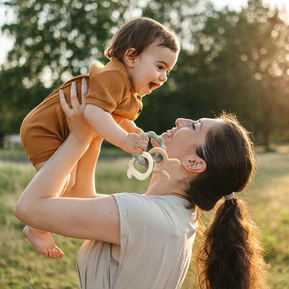 Maman levant son bébé en tenant un anneau de dentition
