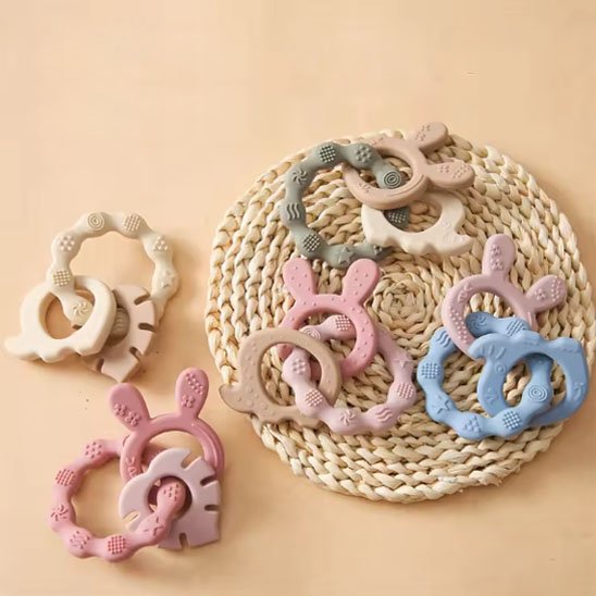 Pack de plusieurs anneaux de dentition en silicone coloré posés sur table